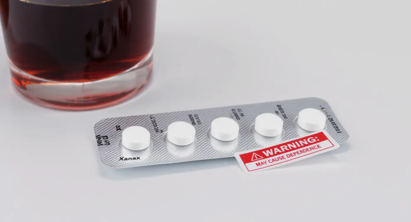 Xanax prescription pills and alcohol glass illustrating misuse risk
