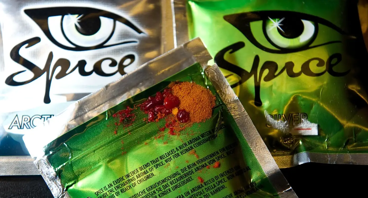Unlabeled herbal-looking substance sold as Spice, with a warning card and ziplock bag marked Herbal Mix on a clean background
