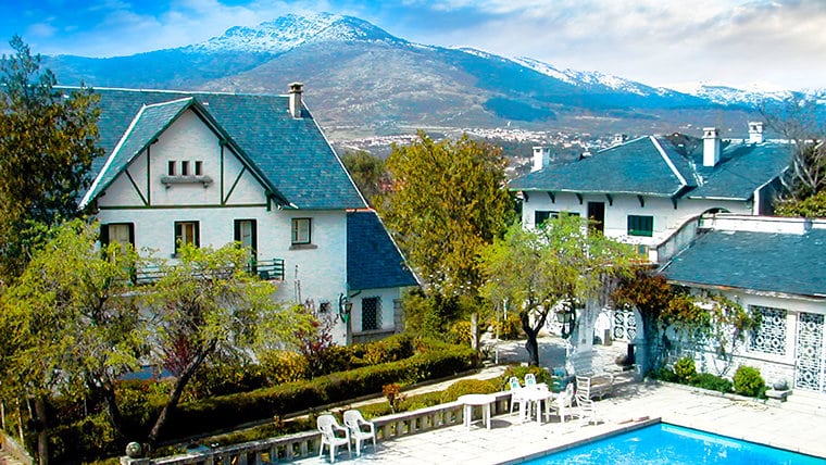 Narconon Los Molinos rehabilitation center in the mountains near Madrid, featuring villa-style buildings, outdoor swimming pool, and scenic mountain views